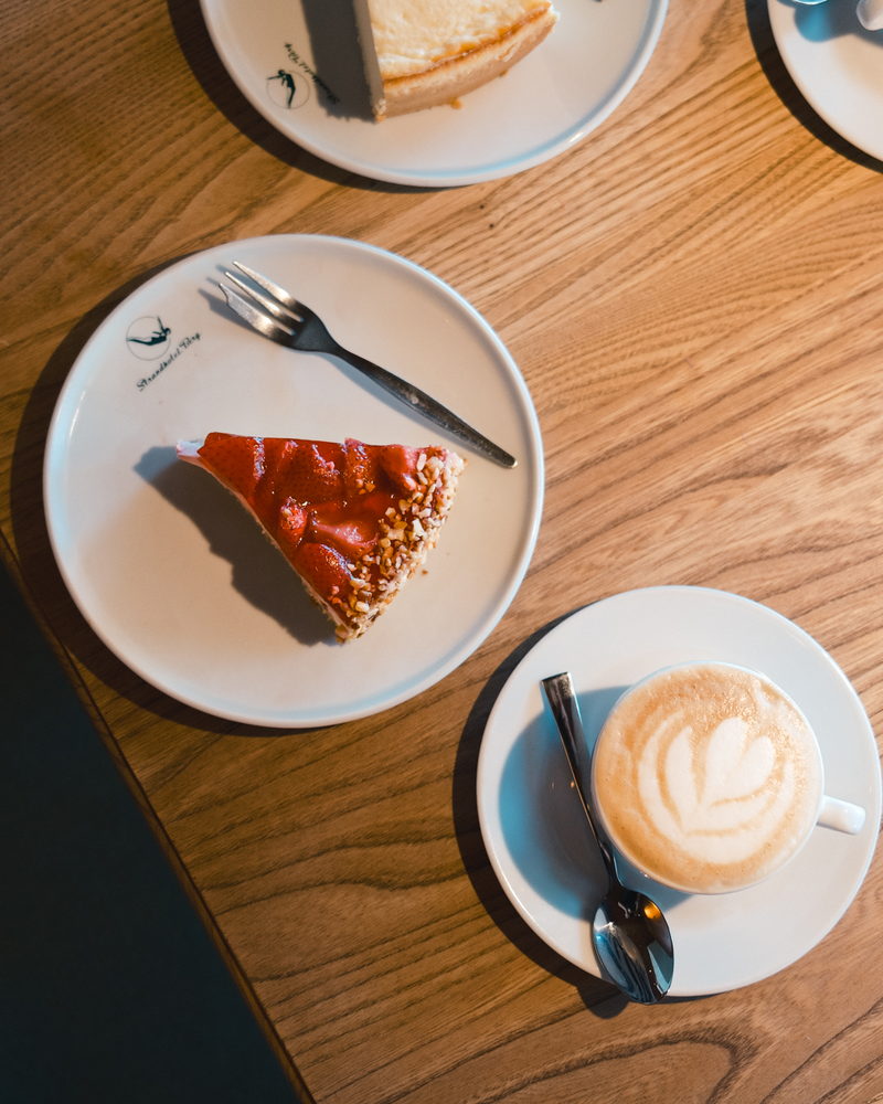 Erdbeerkuchen und Cappuccino auf einem Holztisch, von oben fotografiert